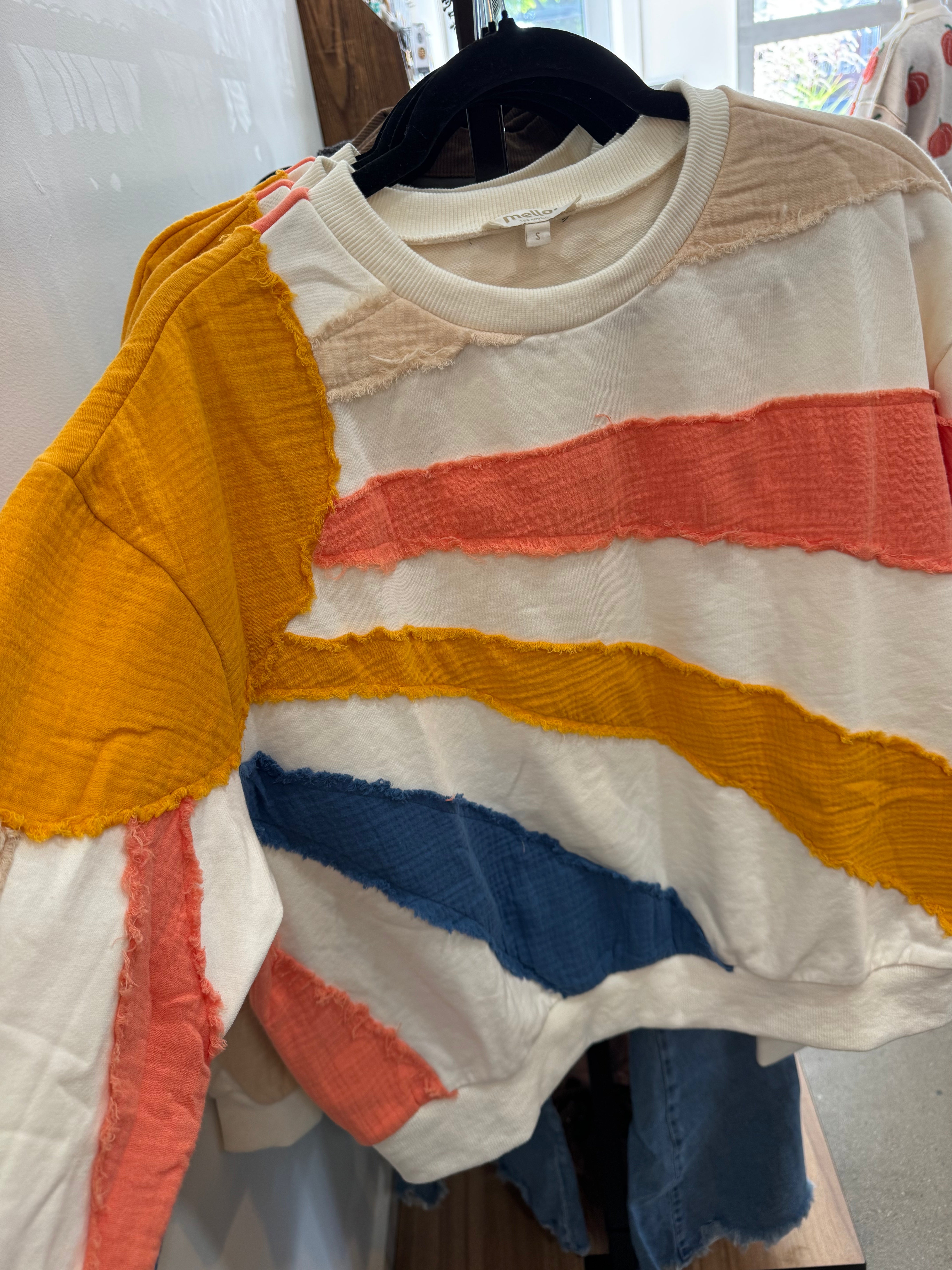 White sweatshirt with patches of fabric that look like rays of sun