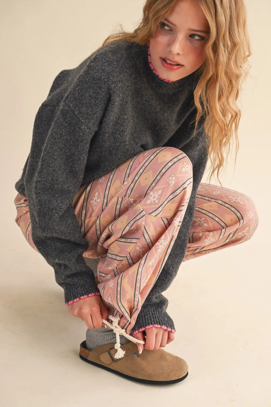 Woman wearing the &merci Aztec Parachute Pants in blush multi print with a charcoal sweater and clogs