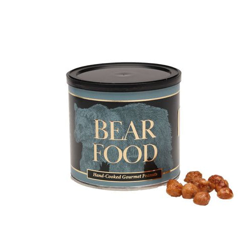 A cylindrical tin of Bear Food hand-cooked gourmet hazelnuts with a few whole hazelnuts placed in front on a plain white background.