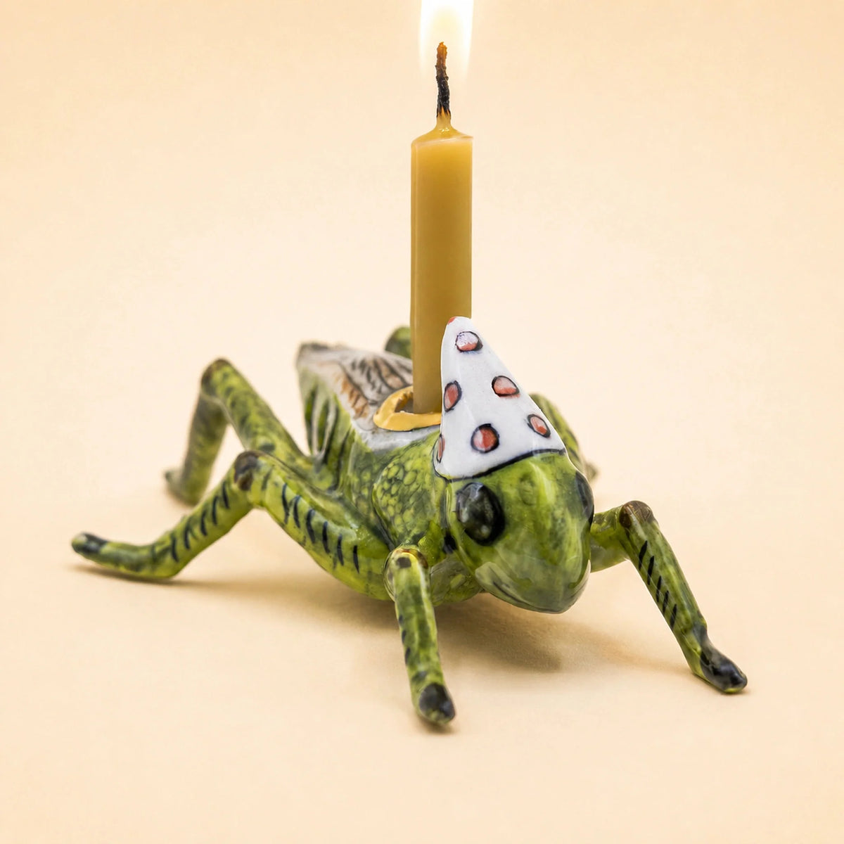 Camp Hollow porcelain cricket cake topper holding a beeswax candle