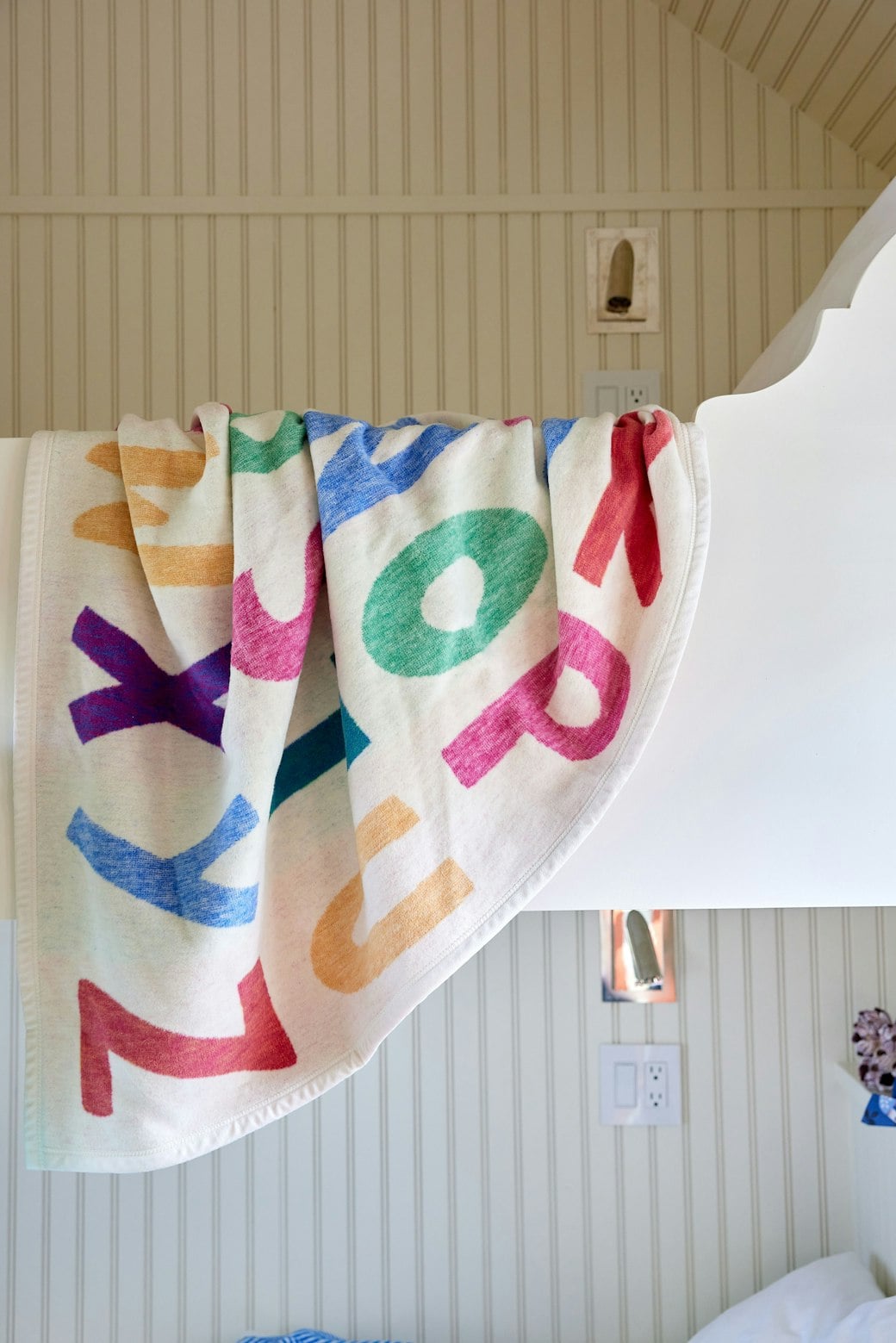 Chappywrap ABC Midi Blanket with colorful alphabet letters hanging in a nursery