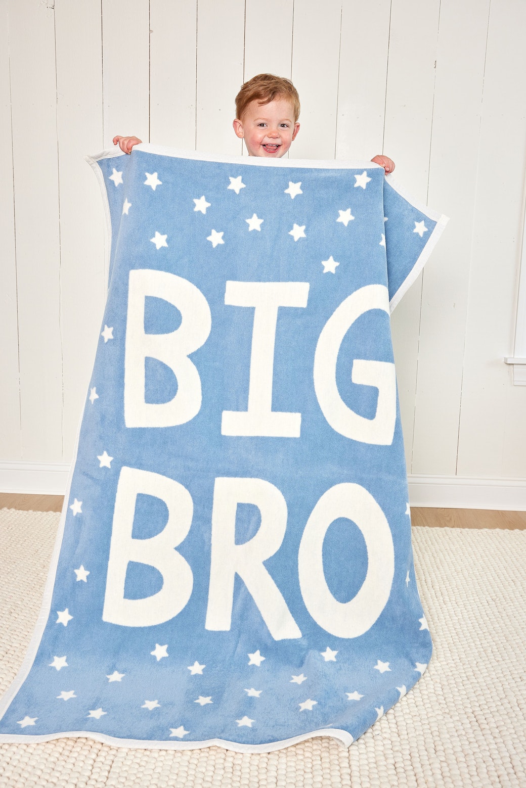 Boy holding up the blue Chappywrap Big Bro Midi Blanket with stars