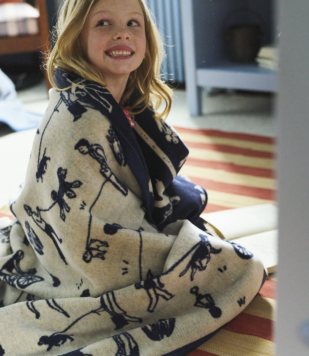 Woman wrapped in the Chappywrap Parkside Pups Midi Blanket indoors