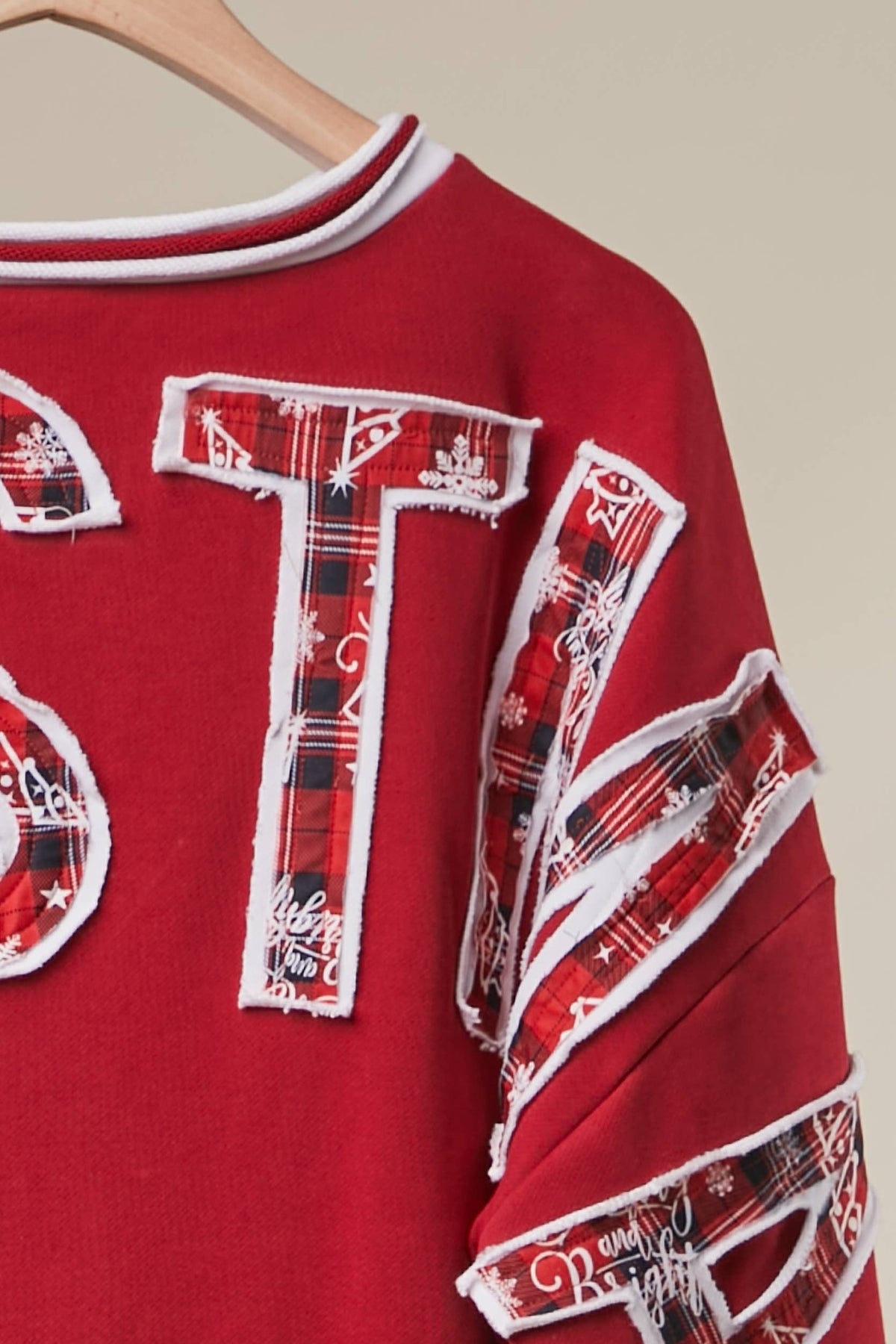 Close-up of the plaid and floral patchwork CHRISTMAS letters on the back of the red sweatshirt