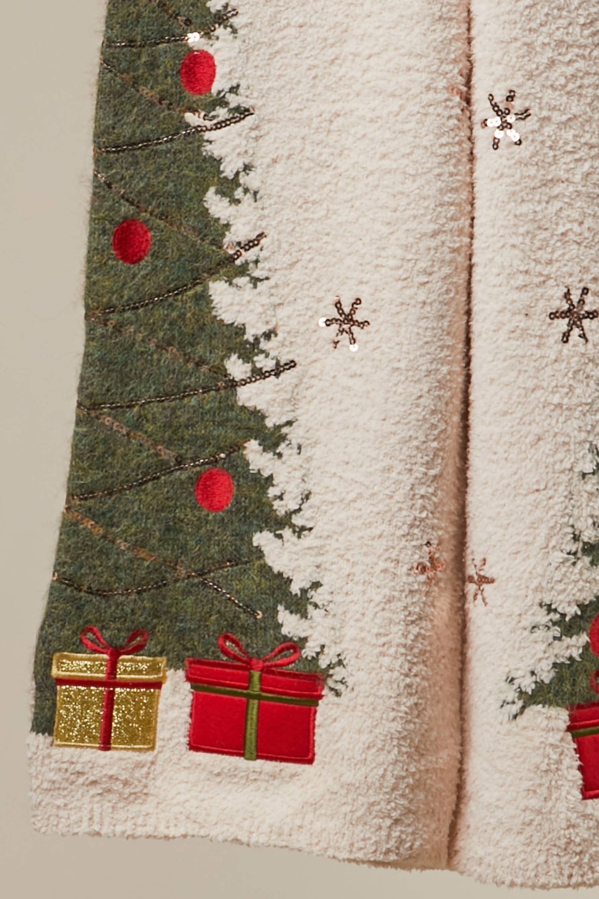 Close-up of the embroidered Christmas tree, red ornaments, and gift boxes on the sweater pants