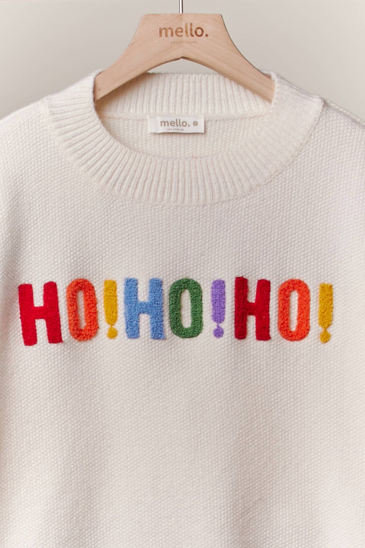 Close-up of the multicolor HO HO HO lettering on the front of the ivory Christmas sweater