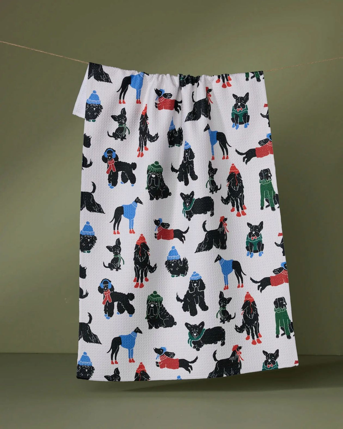 Dogue Magazine tea towel with stylish dogs in colorful coats on a white background hanging on a line
