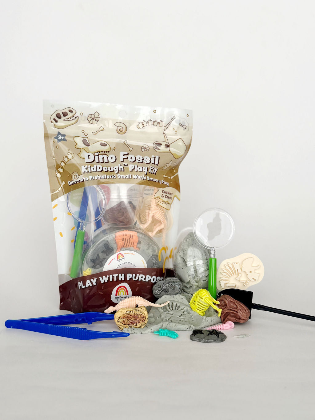 Earth Grown KidDoughs Dino Fossil Dig KidDough Play Kit package with dino fossils and dig tools on white