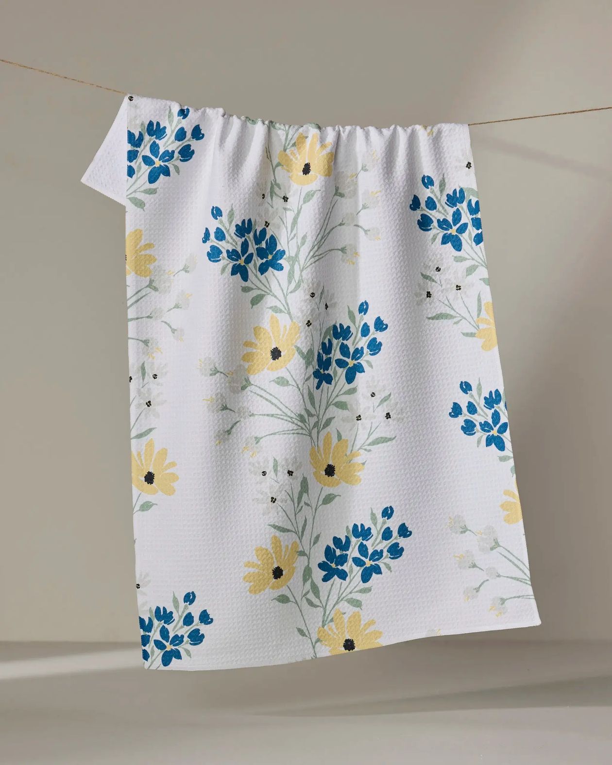 Floral patterned towel hanging on a line against a neutral background