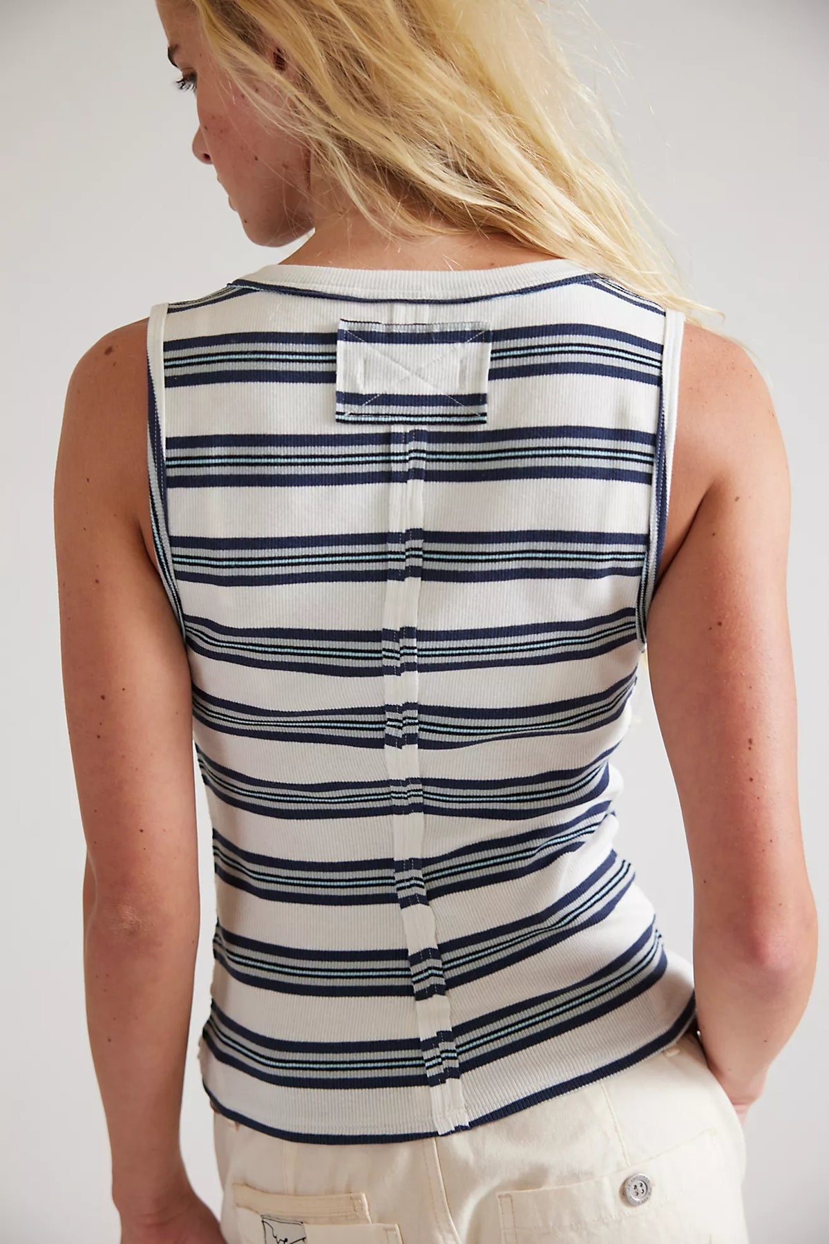 Person wearing a striped sleeveless top with a plain background