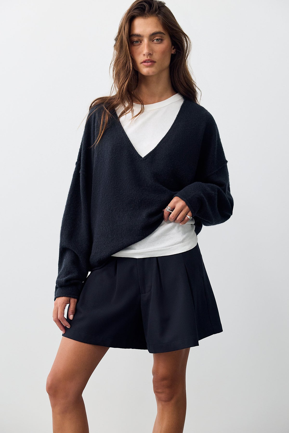 Model wearing the Free People See Me V-Neck Pullover in black with a mini skirt