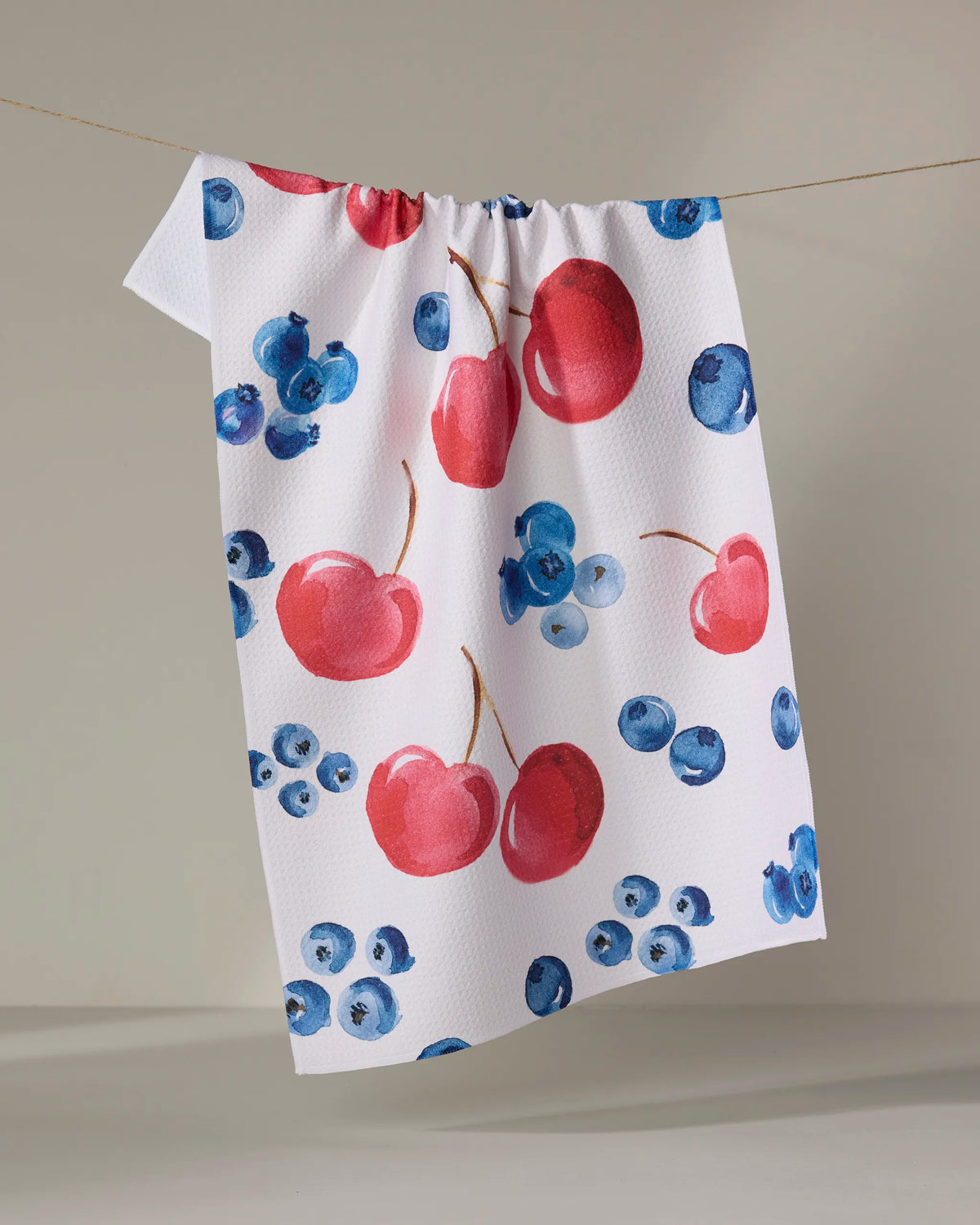 Geometry Cherry On Top tea towel laid flat with a cherry and blueberry print