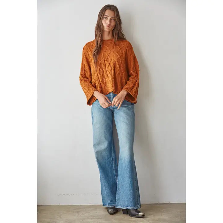 Ginger orange cable-knit cotton pullover sweater with three-quarter sleeves, worn with light wash flare jeans