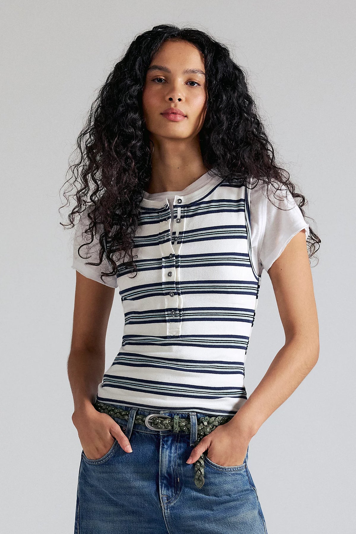 Woman wearing a striped shirt and jeans against a plain background