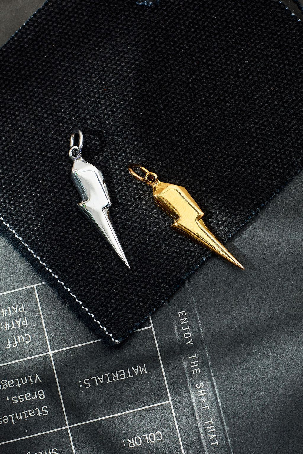 Silver and gold spike-shaped keychains on a black surface with text.