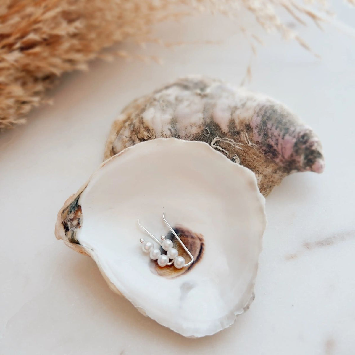 Pearl earring in an oyster shell on a marble surface