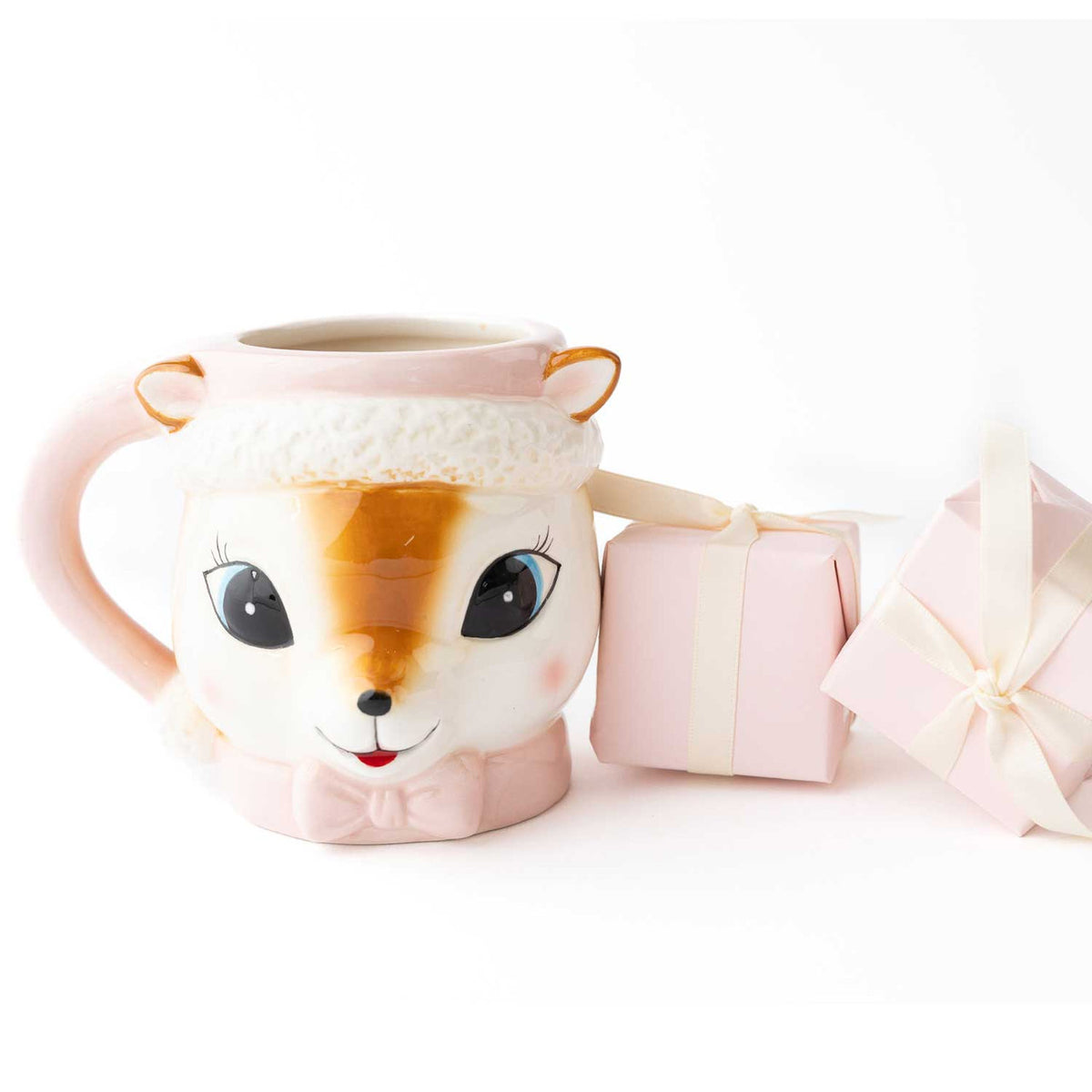 Pink reindeer coffee mug with Santa hat brim shown with pink and white wrapped holiday gift boxes