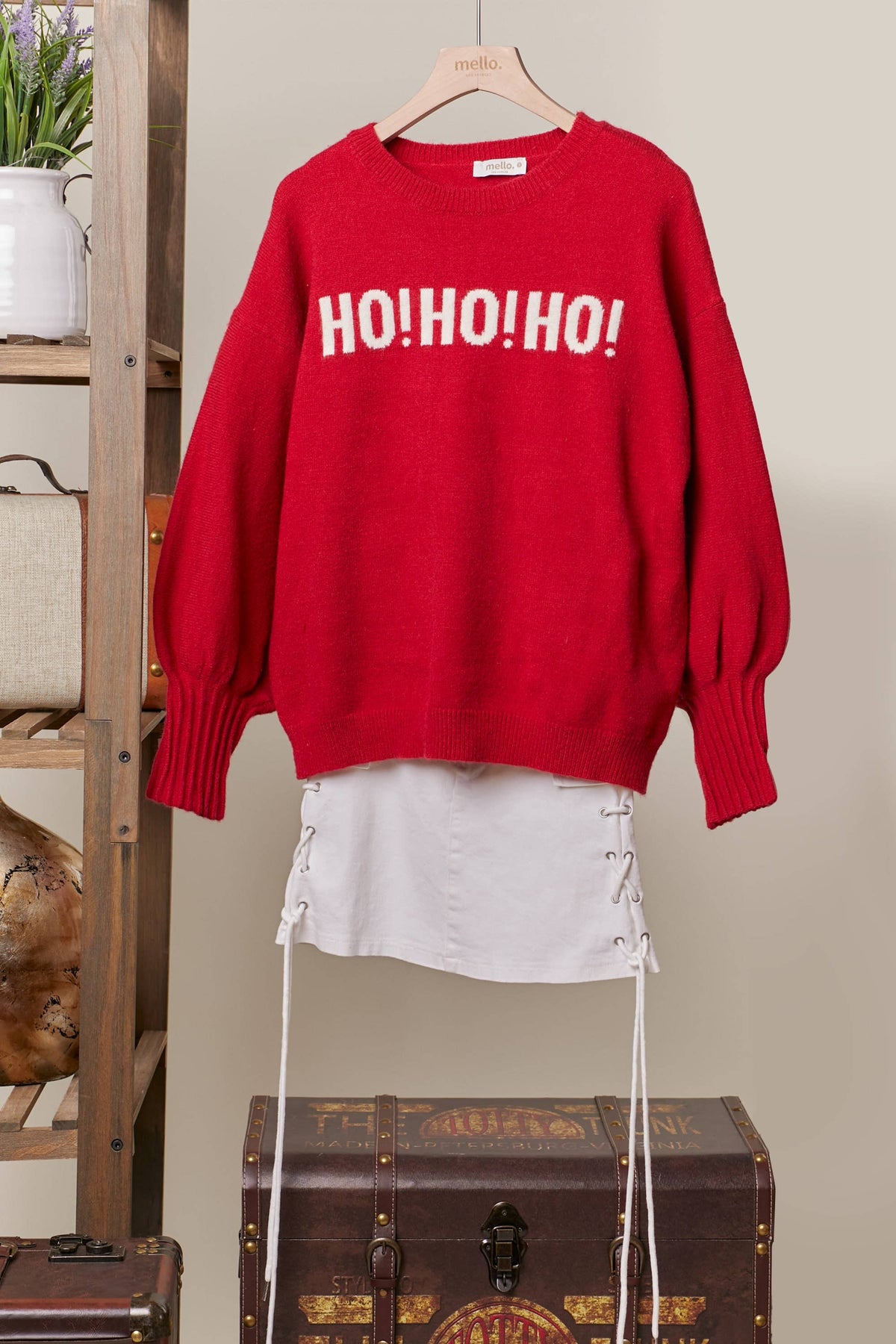 Front of the red oversized Christmas sweater with ivory HO HO HO lettering, on a hanger