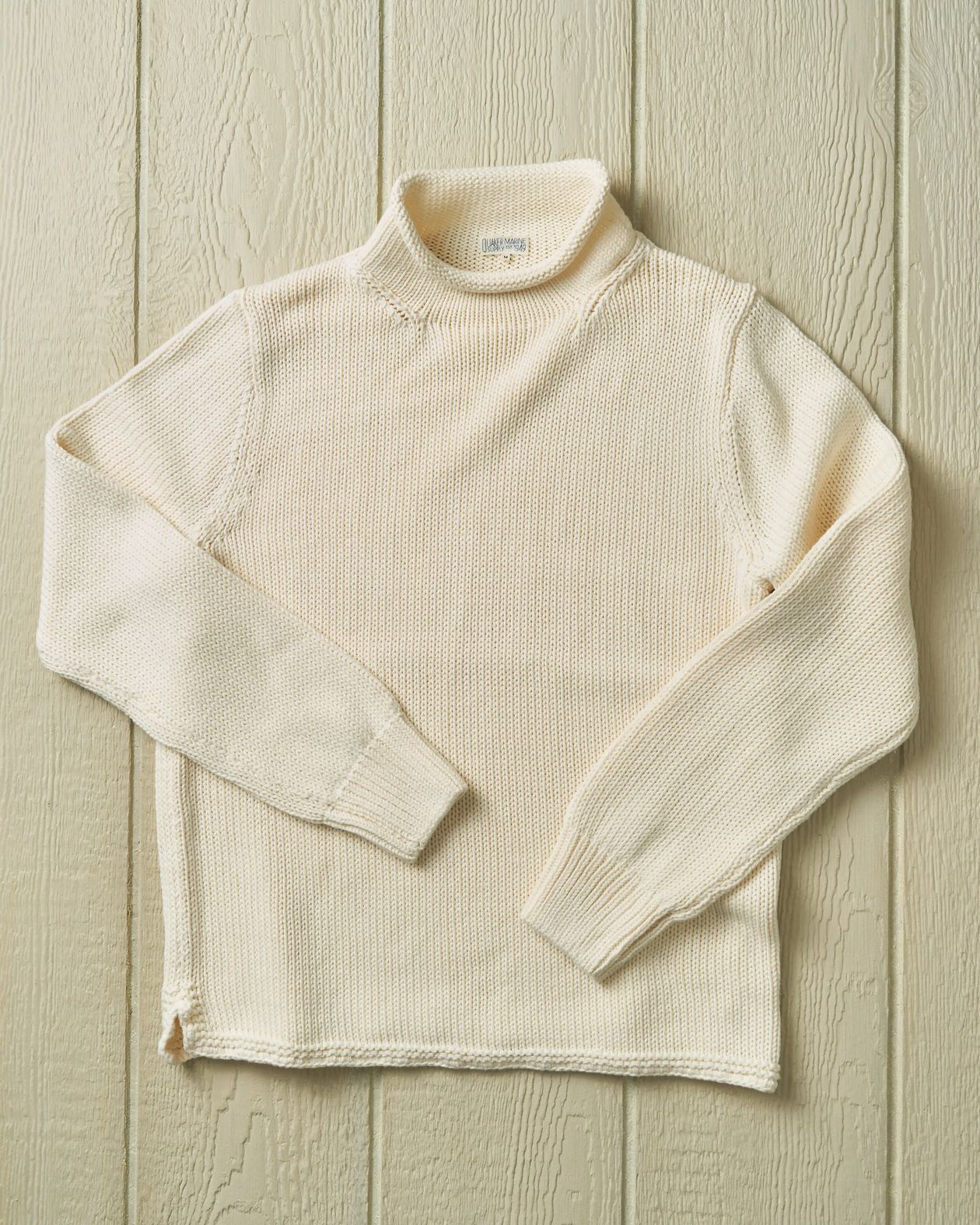 Cream-colored ribbed knit sweater on a wooden surface
