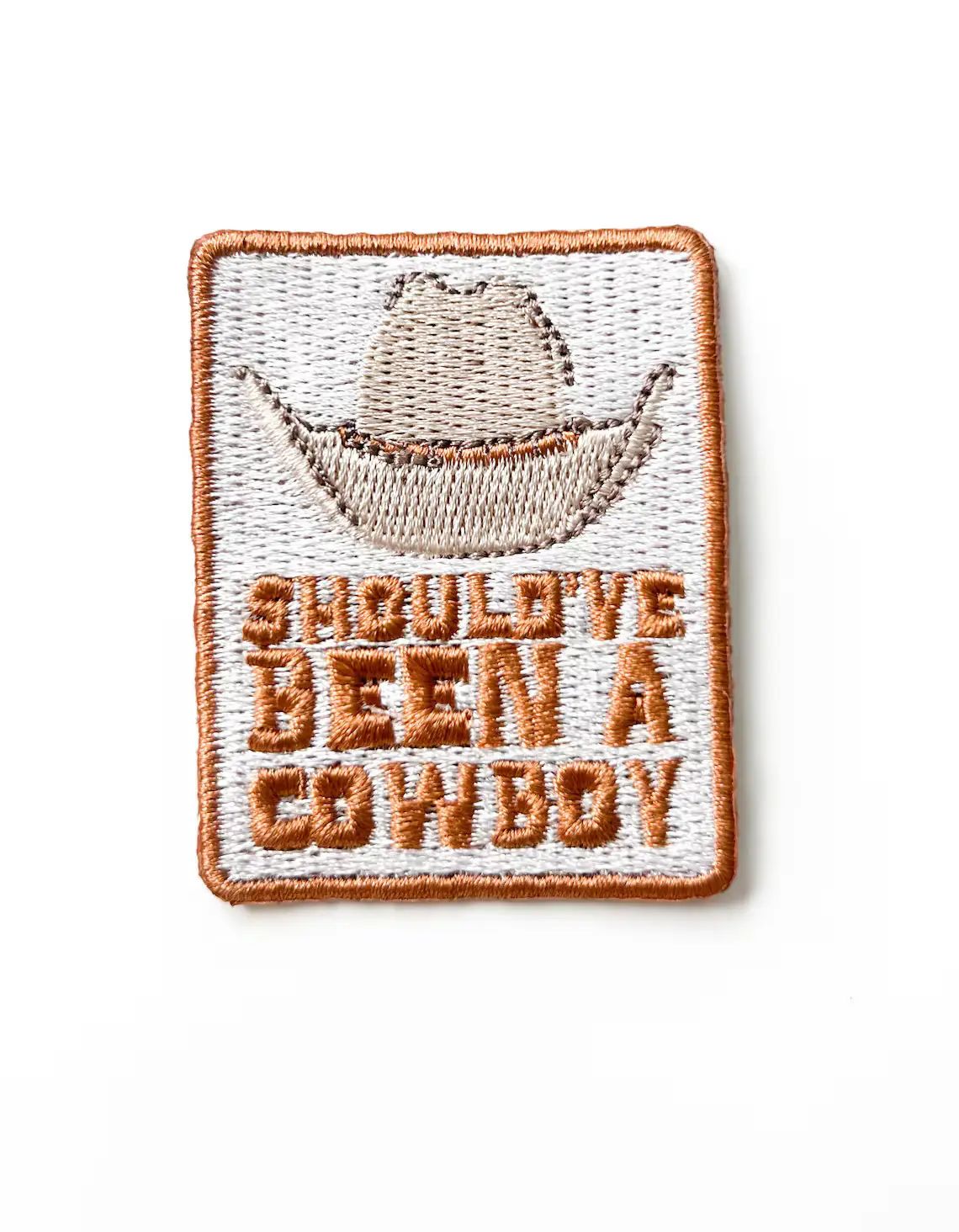 Embroidered patch with a cowboy hat and text Should have been a cowboy on a white background