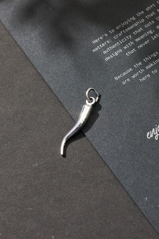 Silver charm on a dark gray surface with text