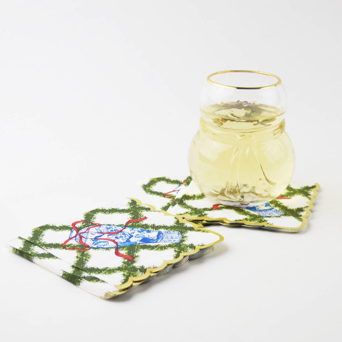 Snowman shaped gold-rimmed glass of white wine on embroidered holiday cocktail napkins