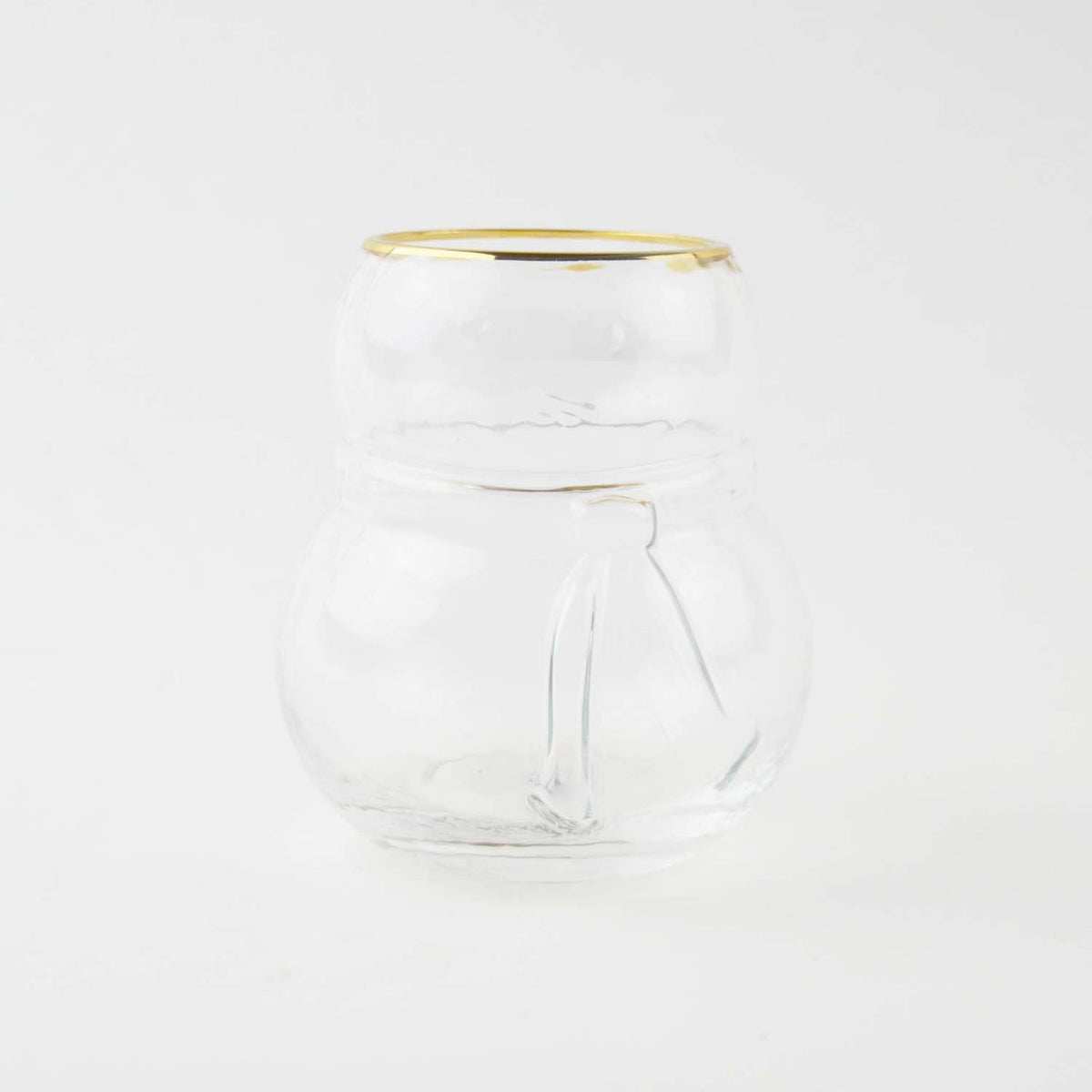 Empty snowman shaped clear drinking glass with a gold rim on a white background