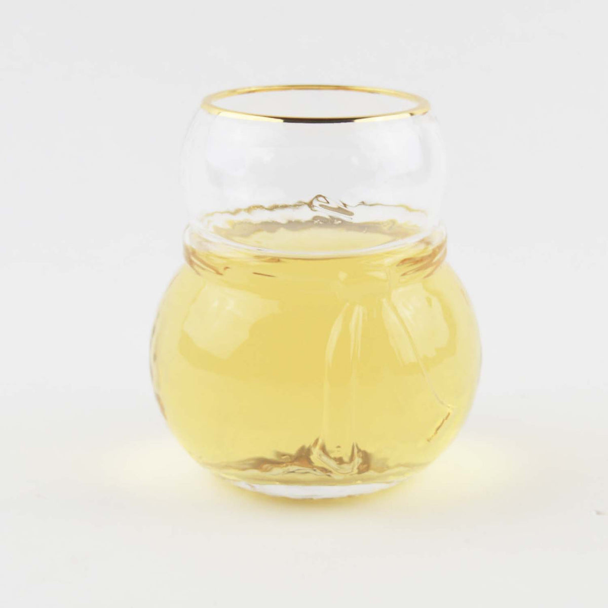 Snowman shaped drinking glass with gold rim filled with white wine on a white background