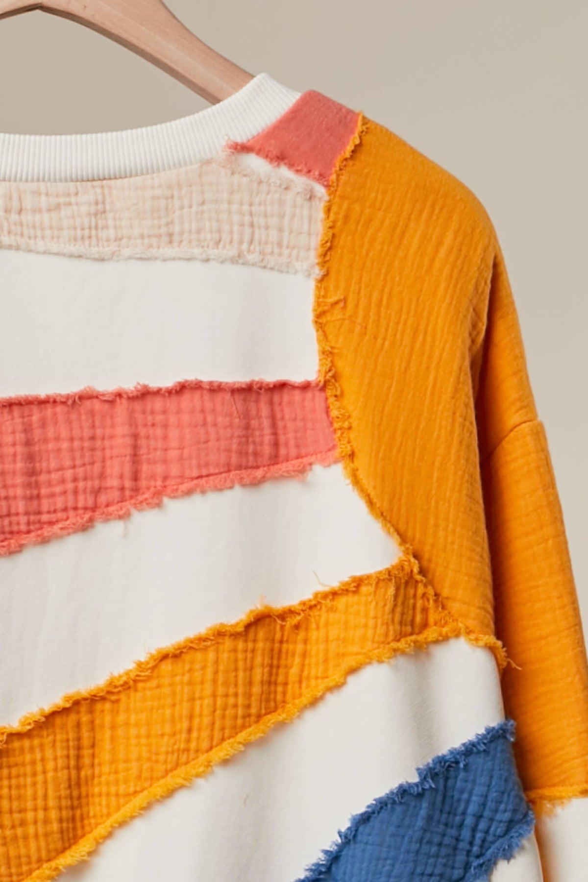 Close-up of the Sun Patchwork Sweatshirt sleeve with marigold and coral patchwork stripes