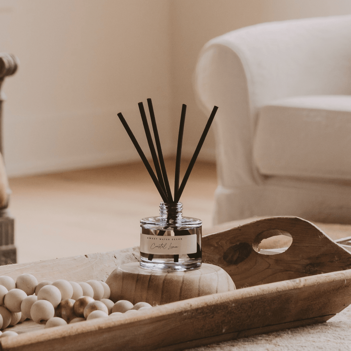 Coastal Lemon reed diffuser with black reed sticks styled on a wooden tray