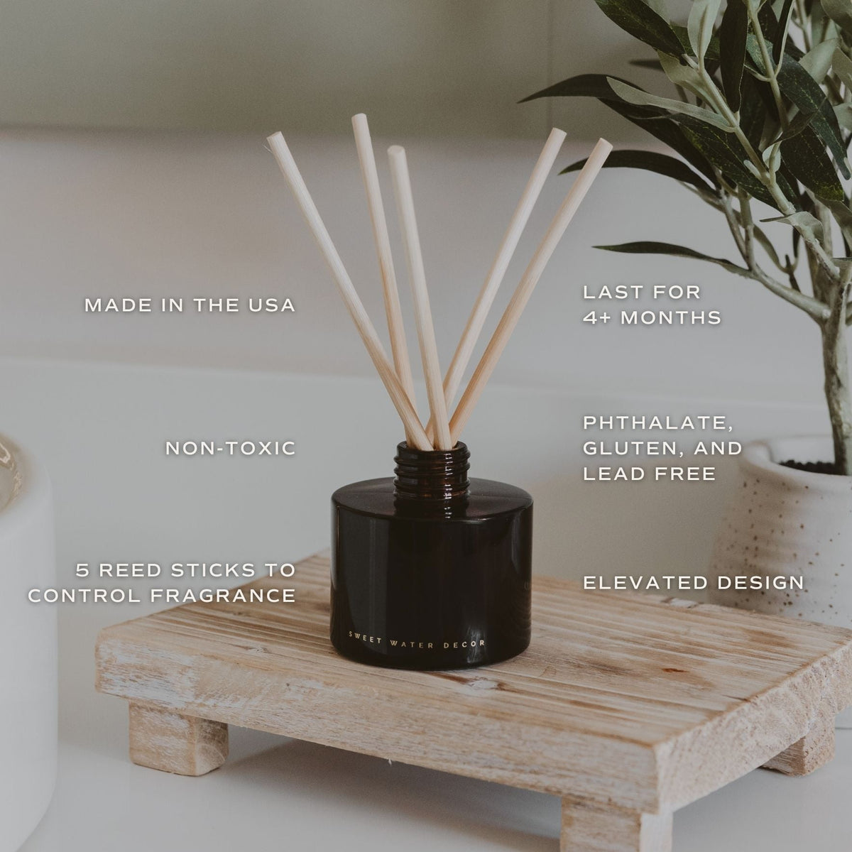 Hello Fall amber reed diffuser on a wooden riser with greenery