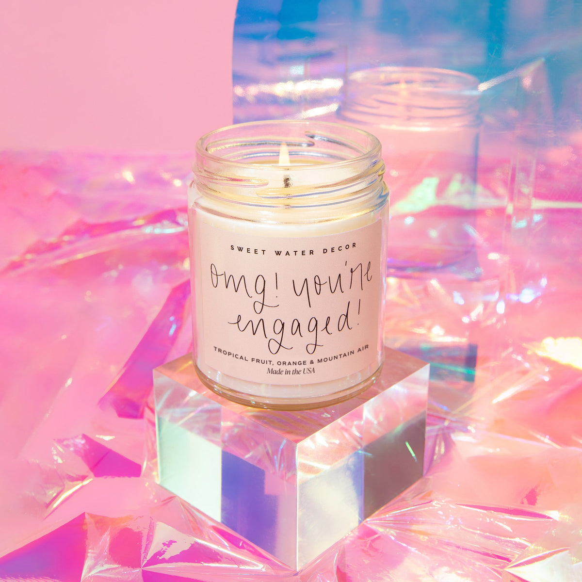 Sweet Water Decor OMG You're Engaged 9 oz soy candle styled on an iridescent backdrop, an engagement gift