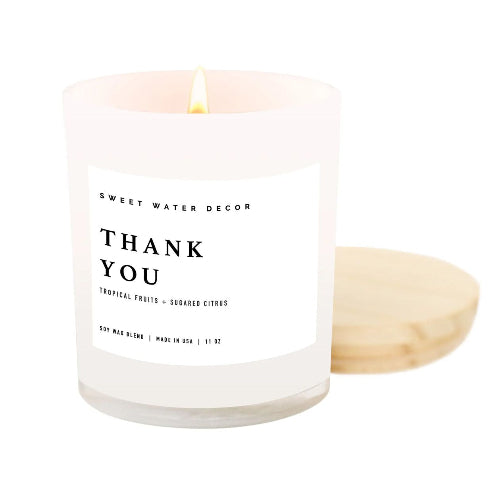 Candle with 'Thank You' label and wooden wick on a white background