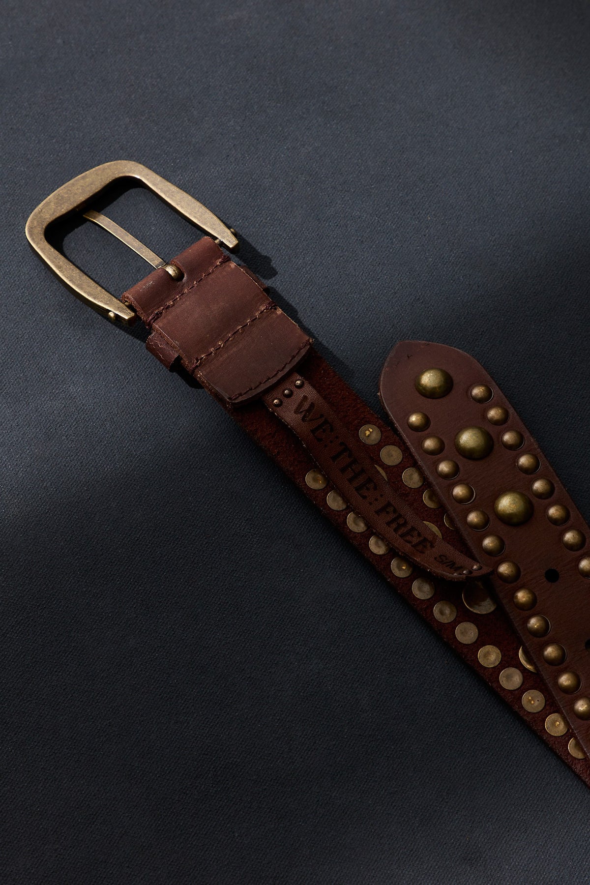 Close-up of the brass buckle and rounded stud detail on the We The Free Sola Stud Belt in cognac