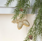 Abbott gold glitter acorns ornament on an evergreen branch