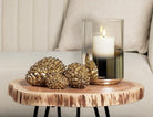 Abbott small antique gold pinecones styled on a wood side table with a candle