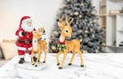 Abbott standing reindeer with bow in a holiday scene with Santa and a Christmas tree