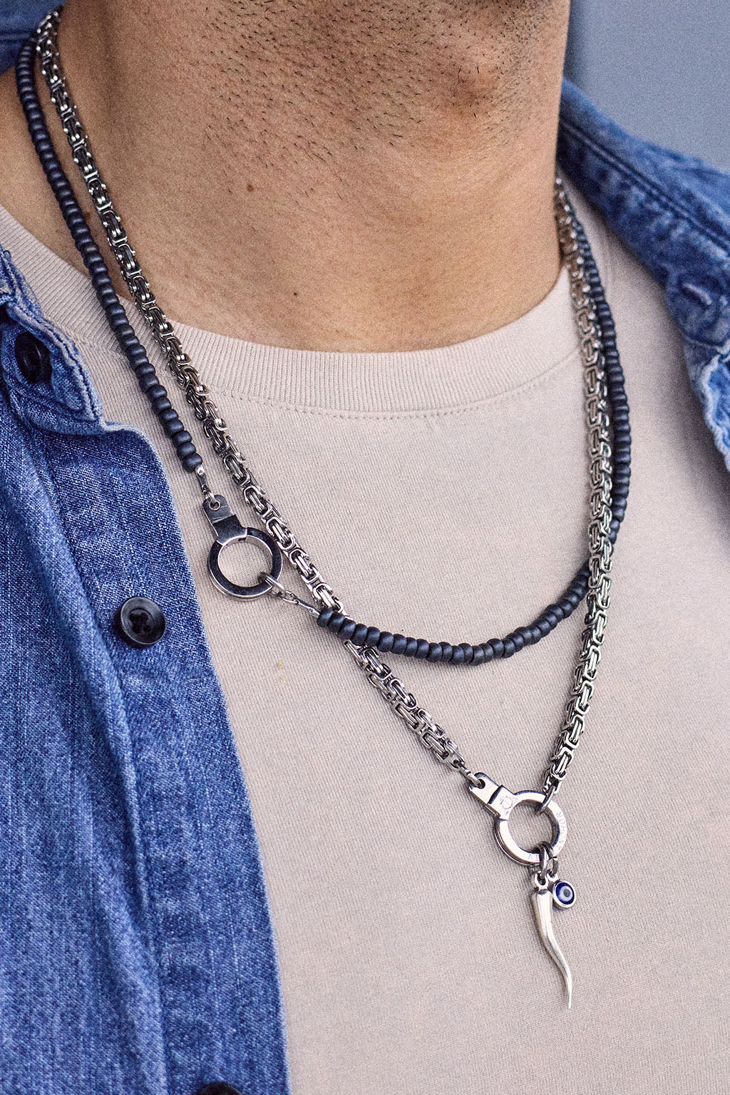 Man wearing the Air and Anchor Italian horn charm necklace layered