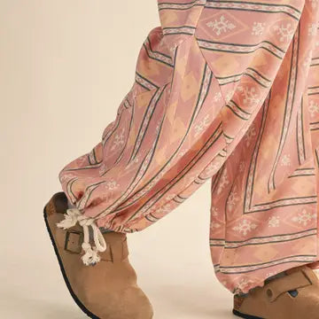 Close-up of the &merci Aztec Parachute Pants showing the drawcord toggle ankle cuffs in blush Aztec print
