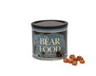 A cylindrical tin of Bear Food hand-cooked gourmet hazelnuts with a few whole hazelnuts placed in front on a plain white background.