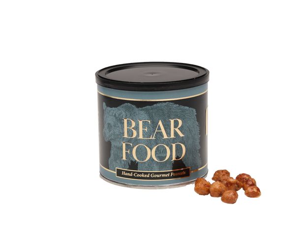 A cylindrical tin of Bear Food hand-cooked gourmet hazelnuts with a few whole hazelnuts placed in front on a plain white background.