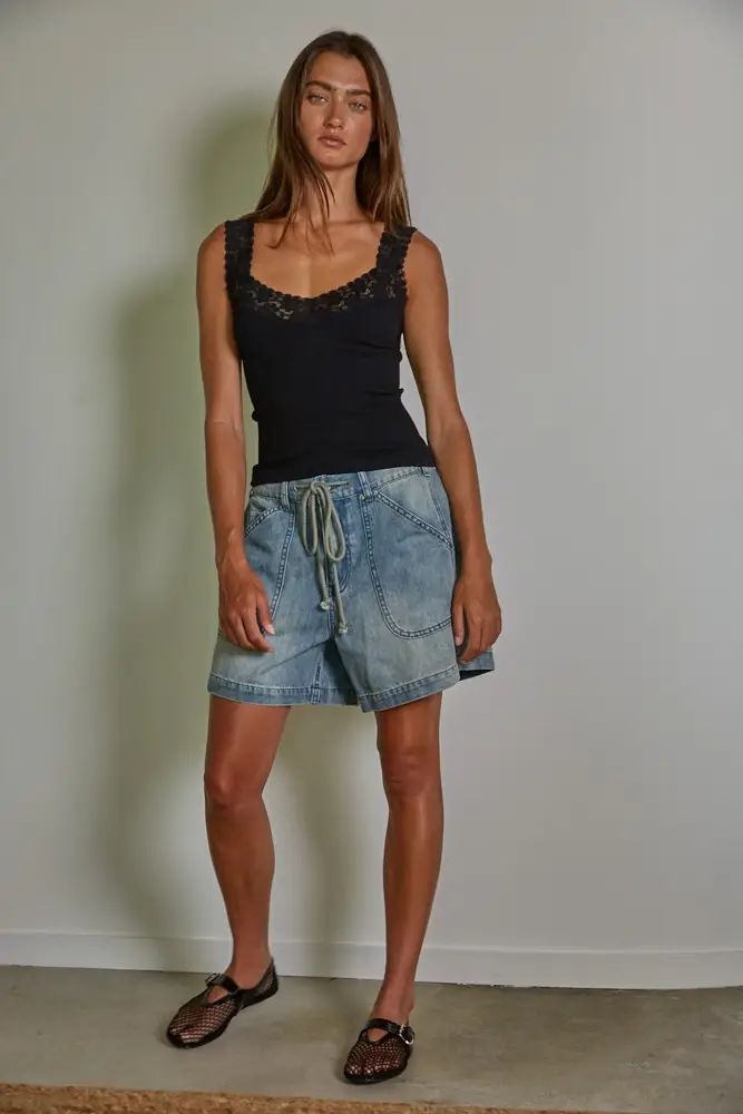 Black seamless ribbed knit tank top with lace trim at the scoop neckline and straps, styled with denim shorts