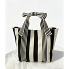 Black and white striped tote bag with a bow on a white background