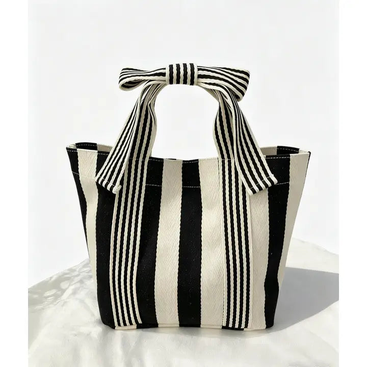Black and white striped tote bag with a bow on a white background