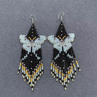 Beaded earrings with black, blue, and yellow beads on a gray background