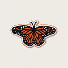 Butterfly patch with orange and black wings on a beige background