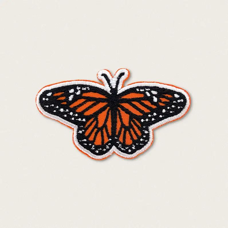 Butterfly patch with orange and black wings on a beige background