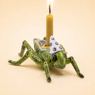 Camp Hollow porcelain cricket cake topper holding a beeswax candle