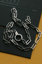 Silver chain and handcuffs on a black surface