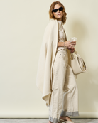 Woman wearing the Chappywrap Bayside Herringbone Shawl in Shell over a cream outfit